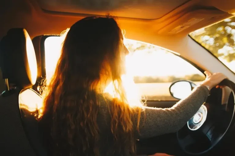 Woman driving with car in harsh sunlight.